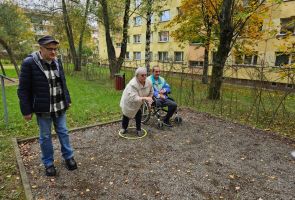 Powiększ zdjęcie: trzy osoby na bulodromie, jedna rzuca bulą