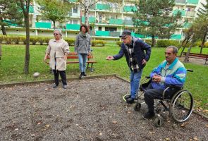 Powiększ zdjęcie: trzy osoby na bulodromie, jedna rzuca bulą