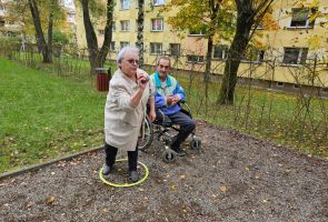 Powiększ zdjęcie: kobieta rzuca bulą, obok mężczyzna na wózku inwalidzkim