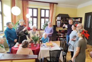 Powiększ zdjęcie: Pani Teresa w otoczeniu gości, którzy śpiewają 100 lat