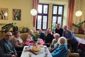 Powiększ zdjęcie: Pani Teresa z gośćmi przy stolikach w kawiarni dps