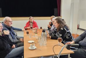 Powiększ zdjęcie: grupa osób przy stoliku podczas rozmów pijąca kawę