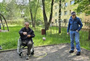 Powiększ zdjęcie: mężczyzna na wózku rzucający boulę, obok dwaj mężczyźni
