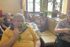 Powiększ zdjęcie: mężczyzna i kobieta wąchają zioła, w tle inni uczestnicy spotkania