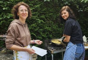 Powiększ zdjęcie: kobieta smażąca jajecznicę i kobieta czekająca na nałożenie porcji