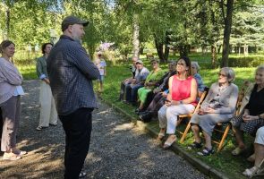 Powiększ zdjęcie: Seniorzy słuchający objaśnienia zasad gry