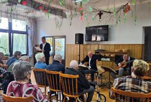 Powiększ zdjęcie: mężczyzna czytający z kartki widziany zza publiczności