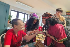 Powiększ zdjęcie: trzy kobiety w strojach Cyganek wróży z ręki kobiecie