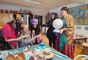 Powiększ zdjęcie: grupa osób w strojach Cyganów wróży z ręki mężczyźnie