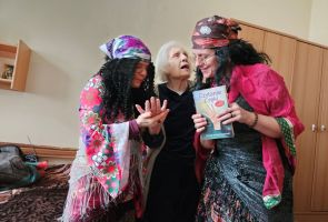 Powiększ zdjęcie: dwie kobiety w strojach Cyganek wróżą z ręki  kobiecie