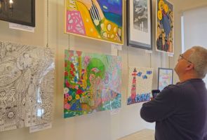 Powiększ zdjęcie: męzczyzna podziwiający prace wiszące na ścianie