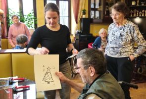 Powiększ zdjęcie: mężczyzna oglądający swoją odbitkę, wokół inni Mieszkańcy