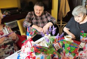 Powiększ zdjęcie: trzy Mieszkanki dps przy stoliku, na którym leżą upominki