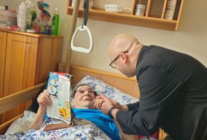 Powiększ zdjęcie: ksiądz składający życzenia starszej kobiecie