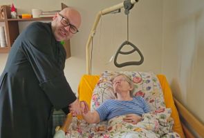 Powiększ zdjęcie: ksiądz składający życzenia starszej kobiecie