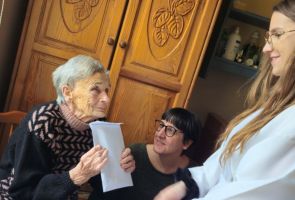 Powiększ zdjęcie: dziewczyna w stroju anioła składająca życzenia starszej kobiecie