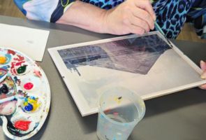 Powiększ zdjęcie: widok dłoni, farb i obrazu malowanego na szkle