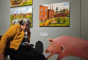 Powiększ zdjęcie: kobieta na wózku oglądająca fragment wystawy