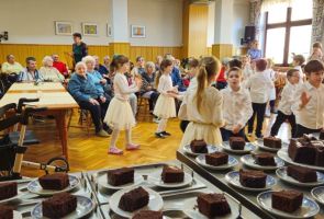 Powiększ zdjęcie: tańczące dzieci, w tle Mieszkańcy oglądający występ