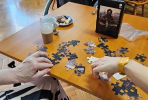 Powiększ zdjęcie: zbliżenie dłoni dwóch osób podczas układania puzzli
