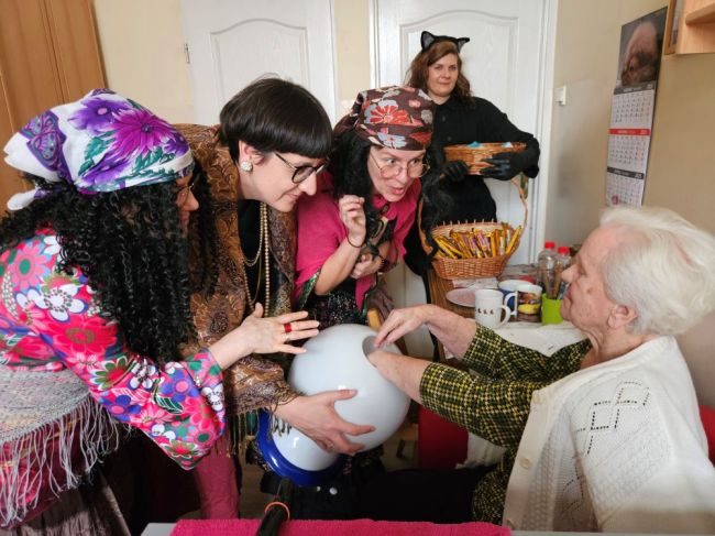 Powiększ zdjęcie: grupa osób w strojach Cyganów wróży starszej kobiecie